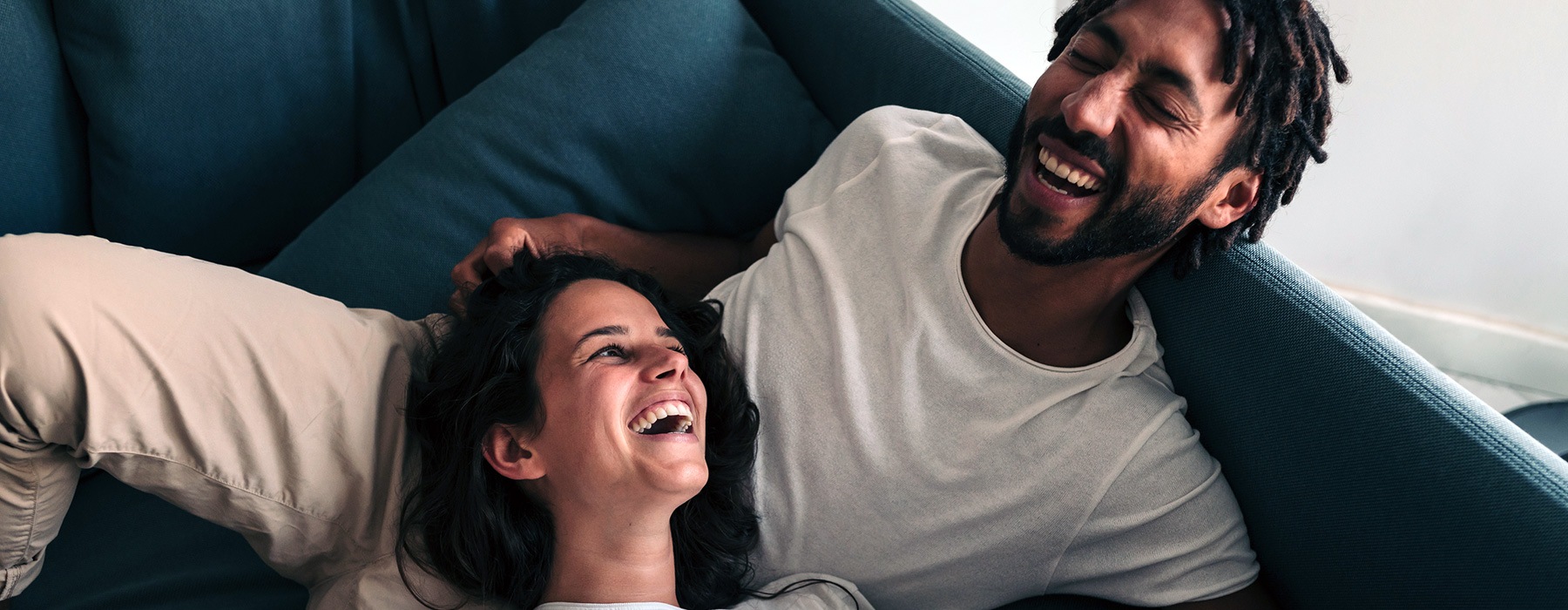 lifestyle image of a couple laughing on a couch