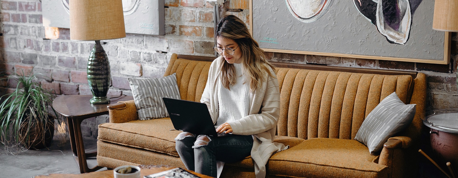 lifestyle image of a young woman sitting on a couch with her laptop